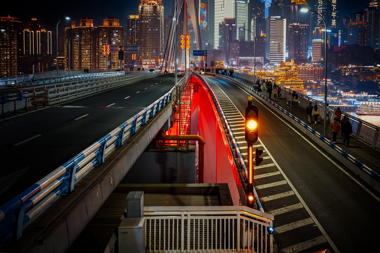 Dynamic night view of Chongqing city skyline from a bridge, featuring vibrant lights and urban architecture.