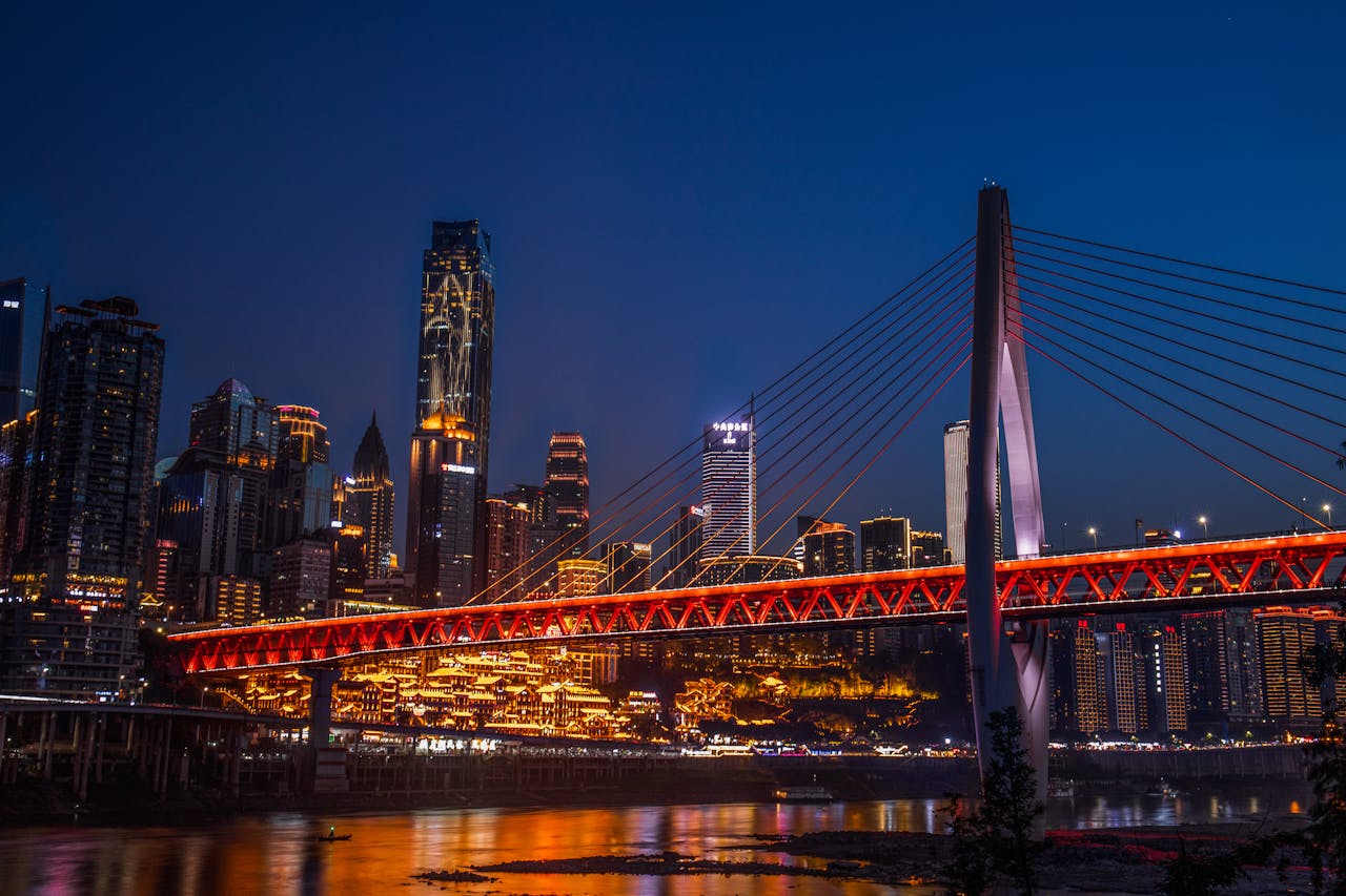 Stunning nighttime view of Chongqing city with illuminated skyscrapers and iconic bridge.